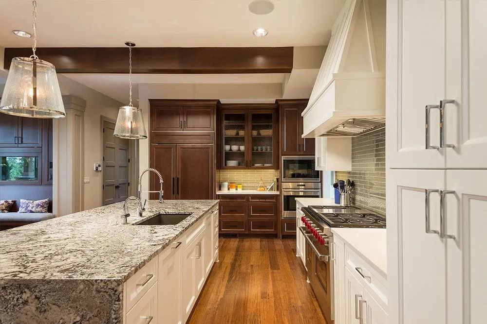 Modern kitchen with granite island, white cabinets, wood floors, and pendant lights