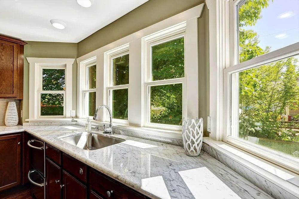 Bright kitchen with marble countertop, sink, and large windows overlooking greenery