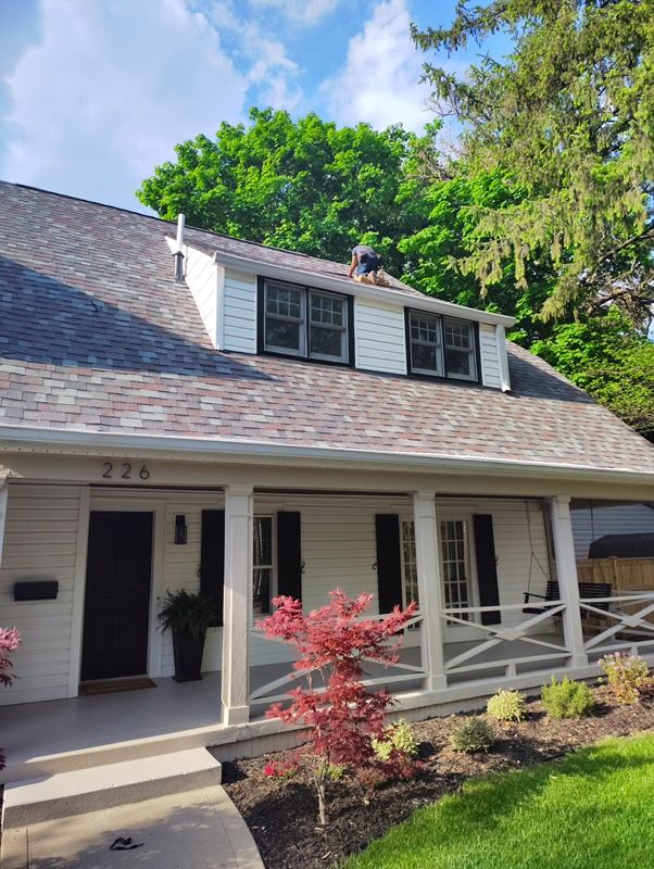 A white house with a gray roof and a porch.