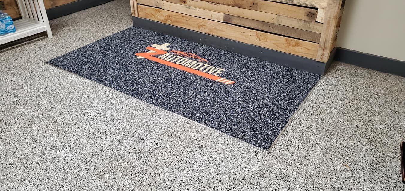 A door mat is sitting on a concrete floor in a room.
