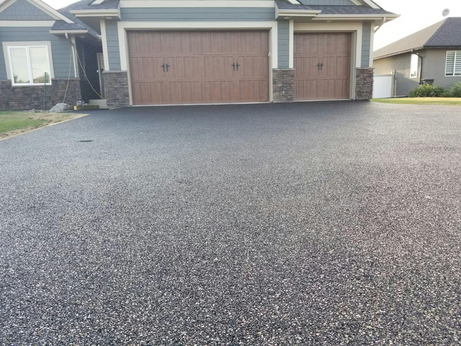A driveway leading to a house with two garage doors.