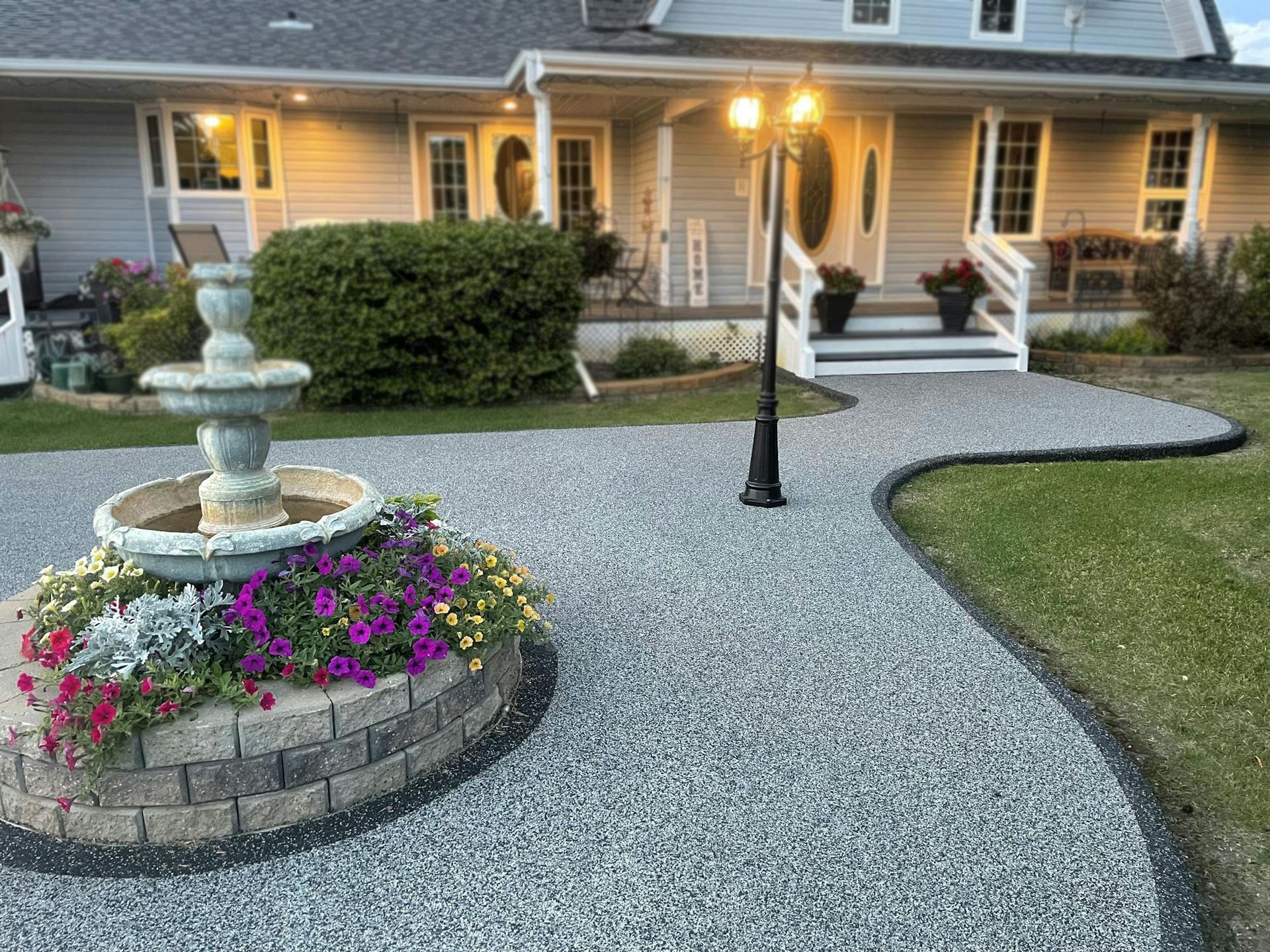 There is a fountain in the middle of the driveway in front of the house.