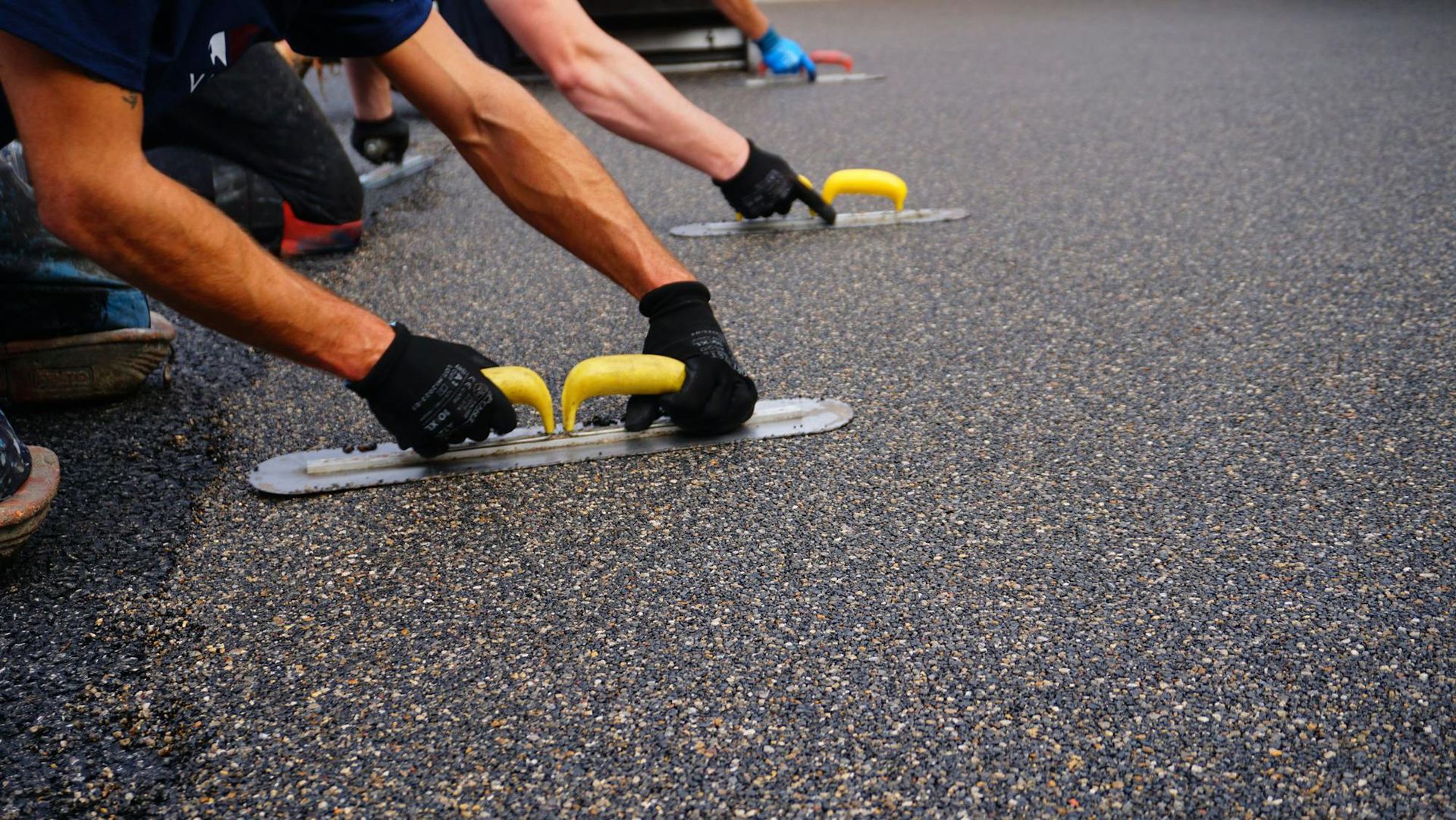 A man is laying a concrete floor with a trowel.