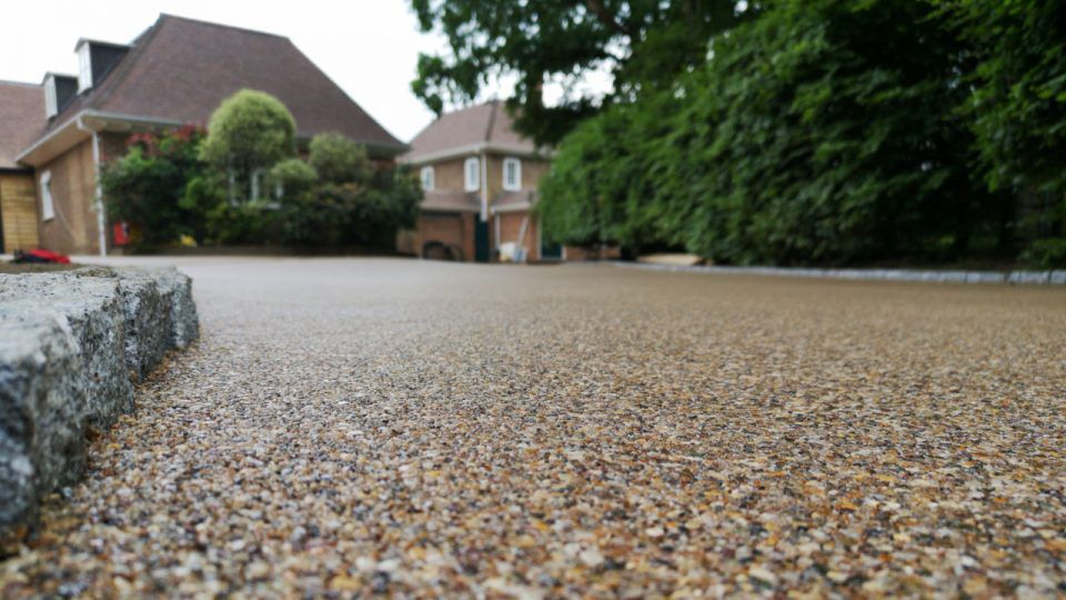 A gravel driveway with a house in the background.