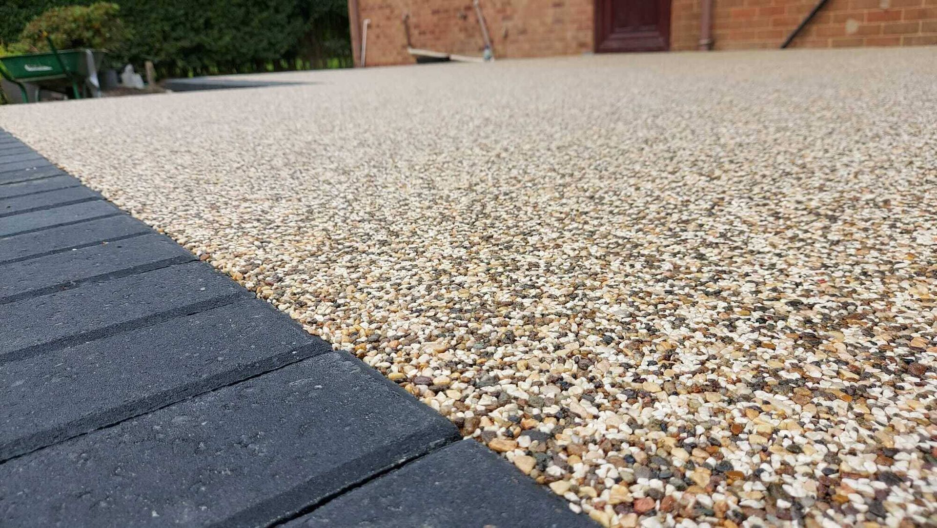 A close up of a gravel driveway with a black curb.