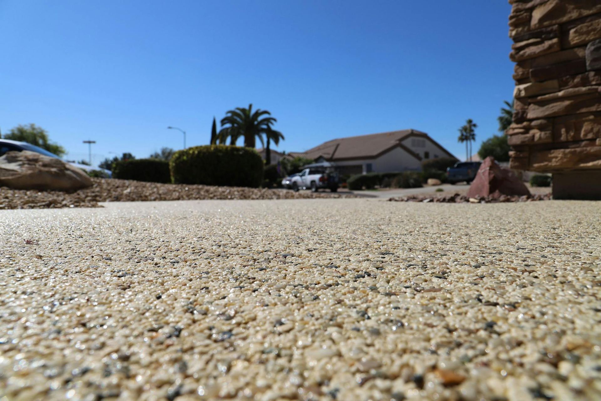 A gravel driveway with a house in the background.