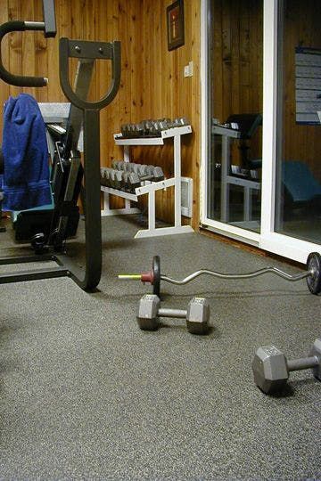 A gym with a barbell and dumbbells on the floor.
