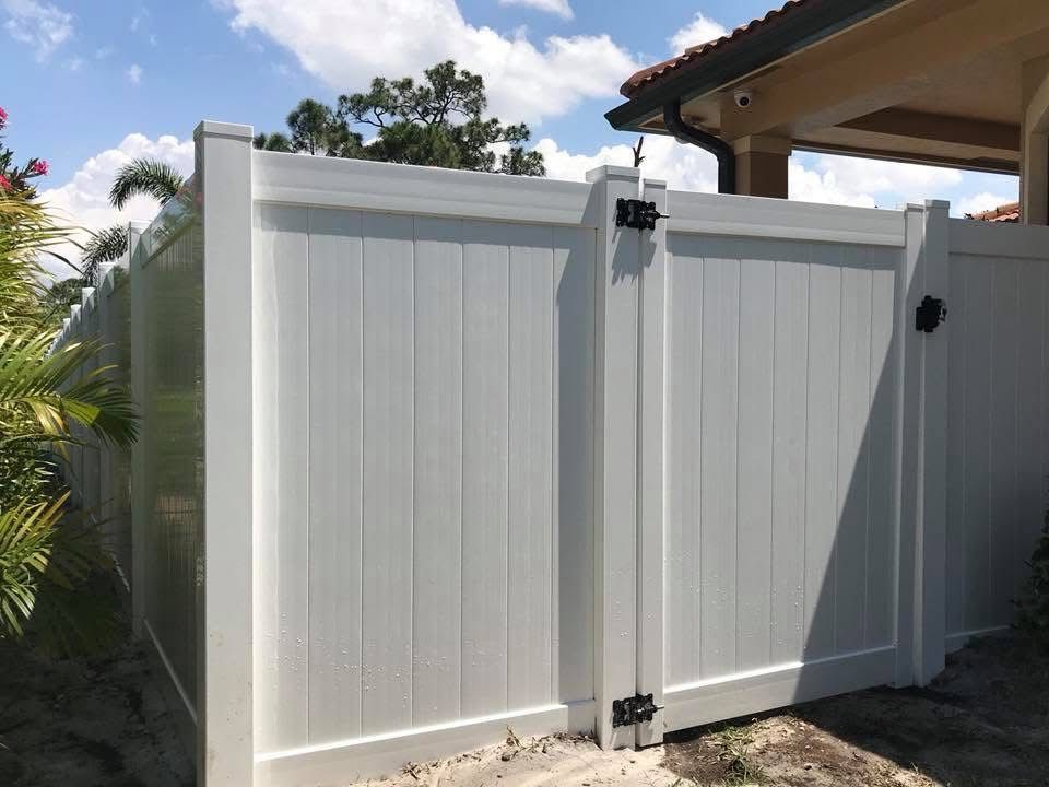 A white fence with a gate in front of a house.