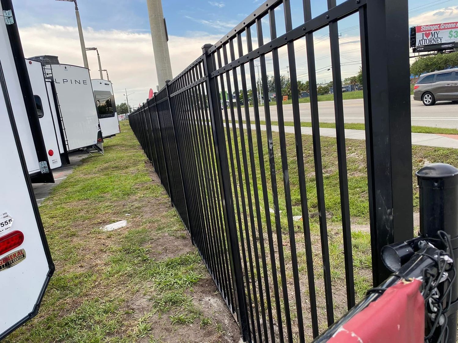 A black metal fence is surrounding a grassy field.