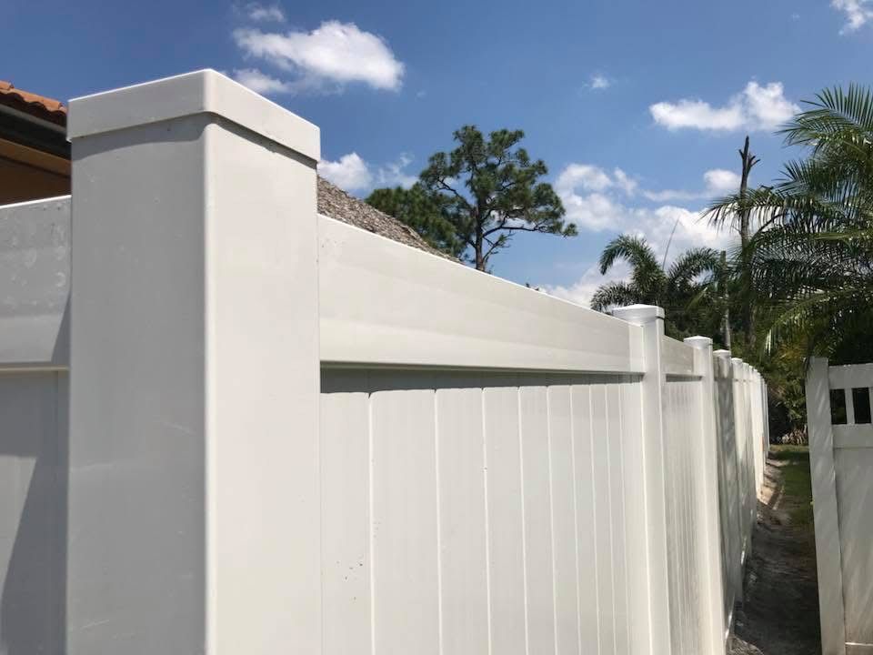 A white vinyl fence with a blue sky in the background.