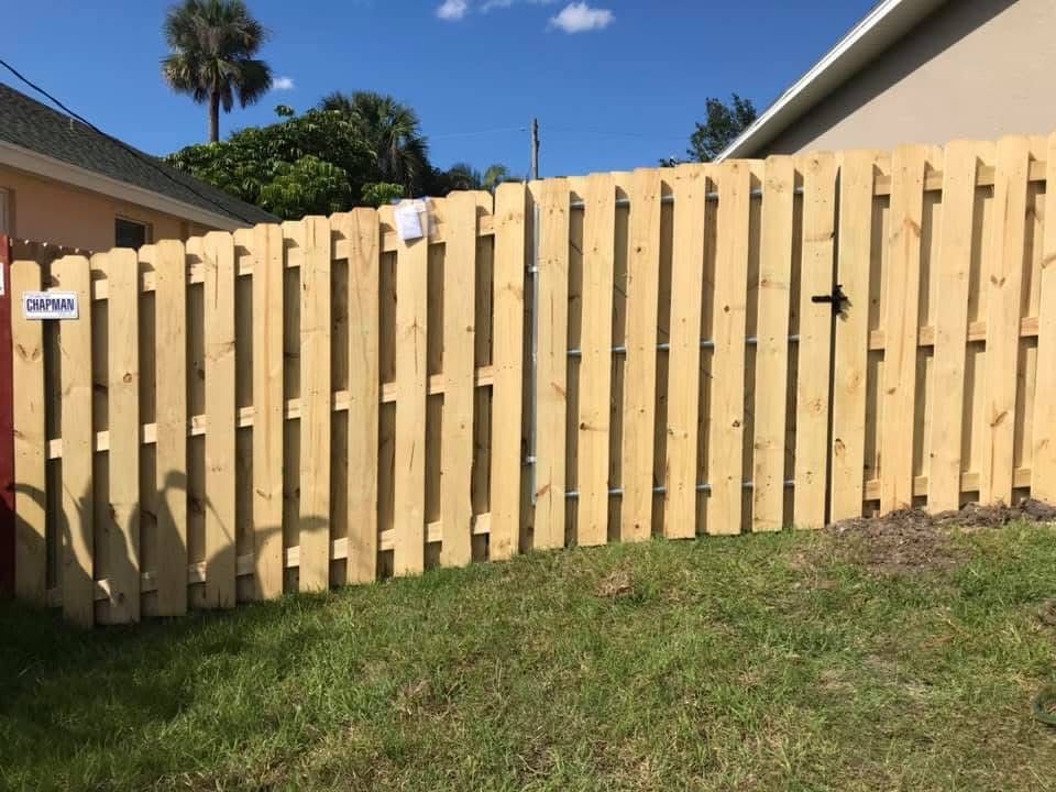 A wooden fence is sitting in the grass in front of a house.