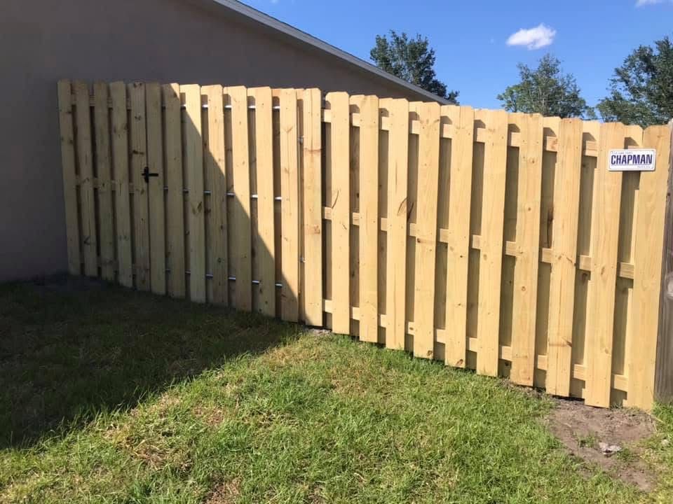 A wooden fence is sitting in the grass in front of a house.