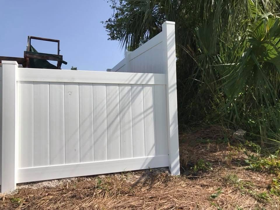 A white fence is sitting on top of a dirt hill.