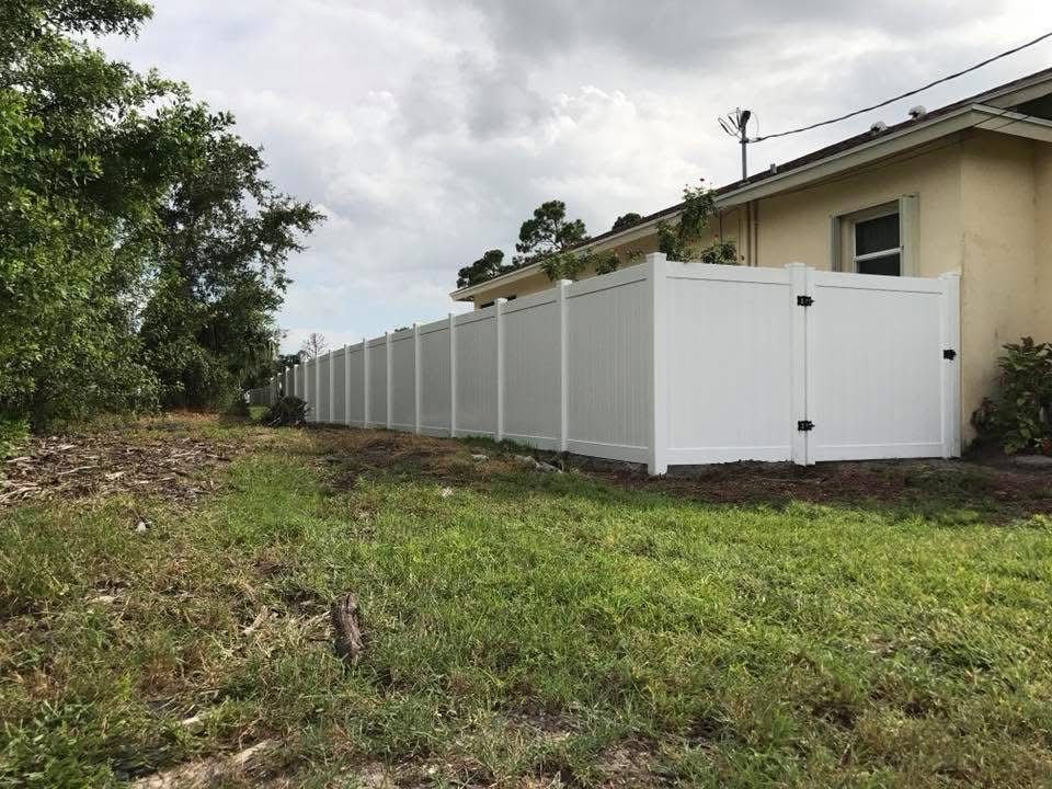 A white fence is sitting in the grass in front of a house.