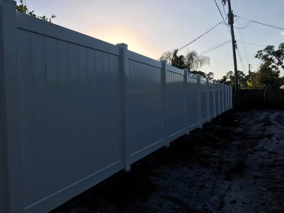 A white fence is sitting on top of a dirt road.