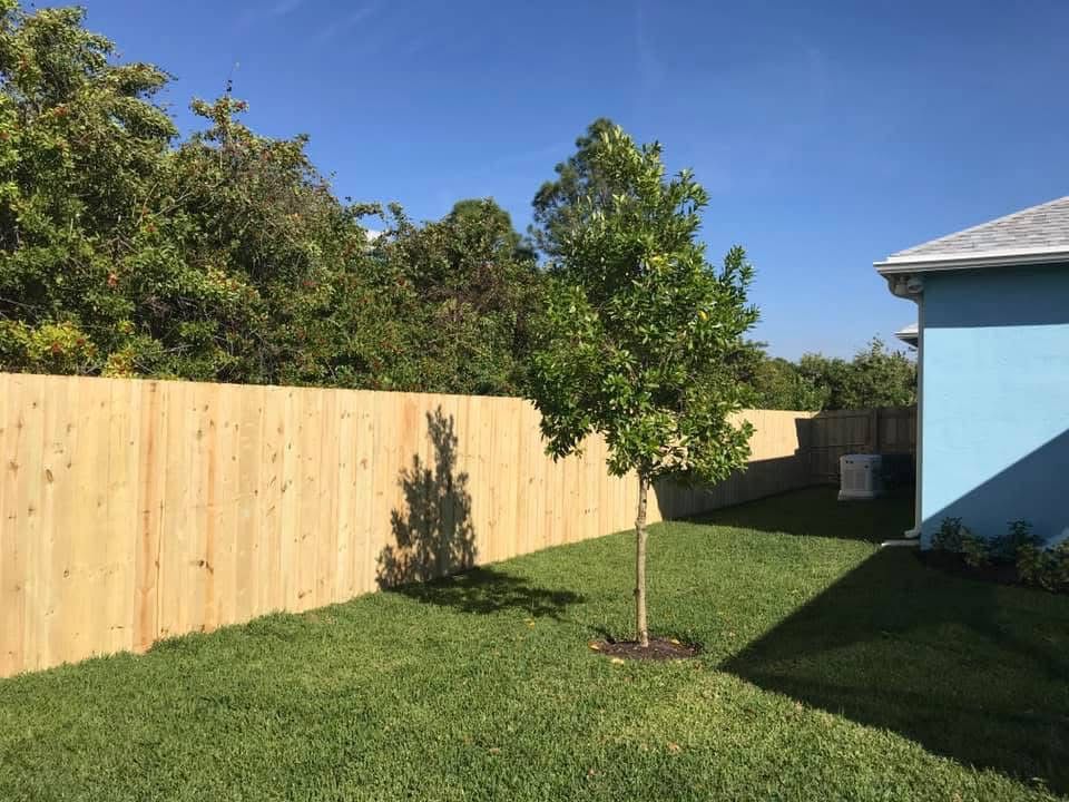 A wooden fence is in the backyard of a house.