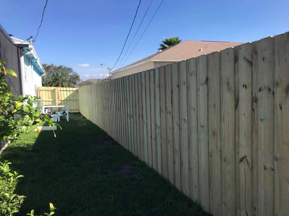 A wooden fence is in the backyard of a house.