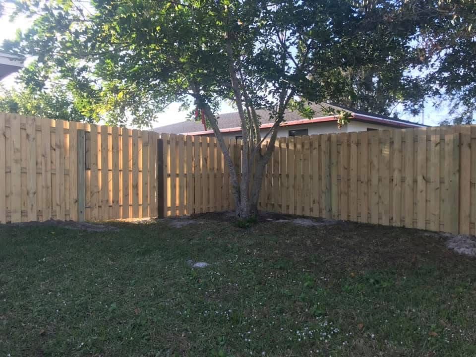 A wooden fence is in the backyard of a house.