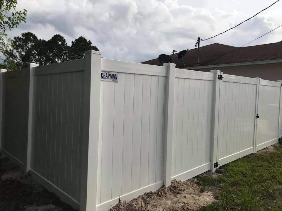 A white fence with a gate and a house in the background