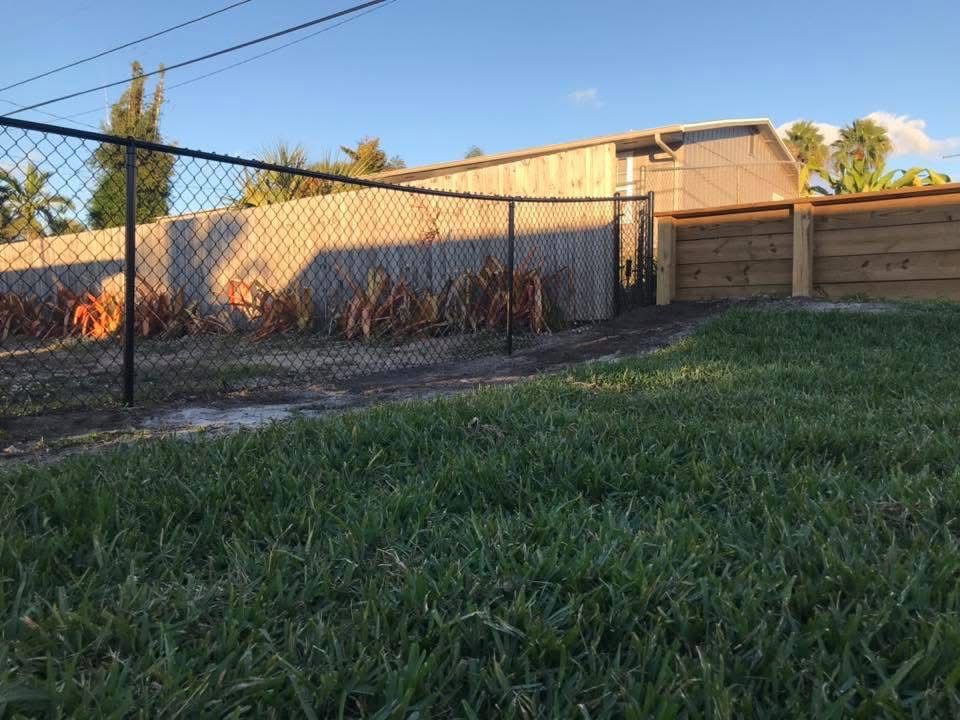 A chain link fence is surrounding a lush green yard.