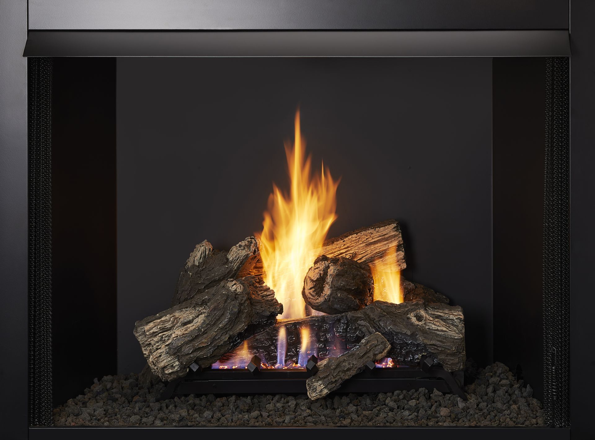 Gas fireplace with burning logs and flames against a black backdrop.