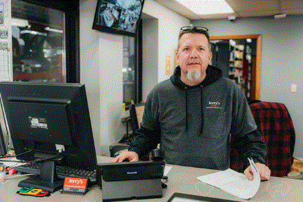 A man is standing at a counter in front of a computer.
