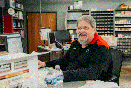 A man is sitting at a desk in a store with a bottle of water.