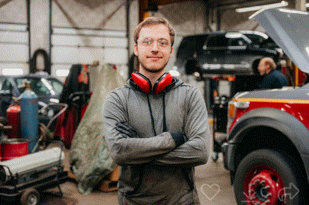 A man is standing in a garage with his arms crossed.