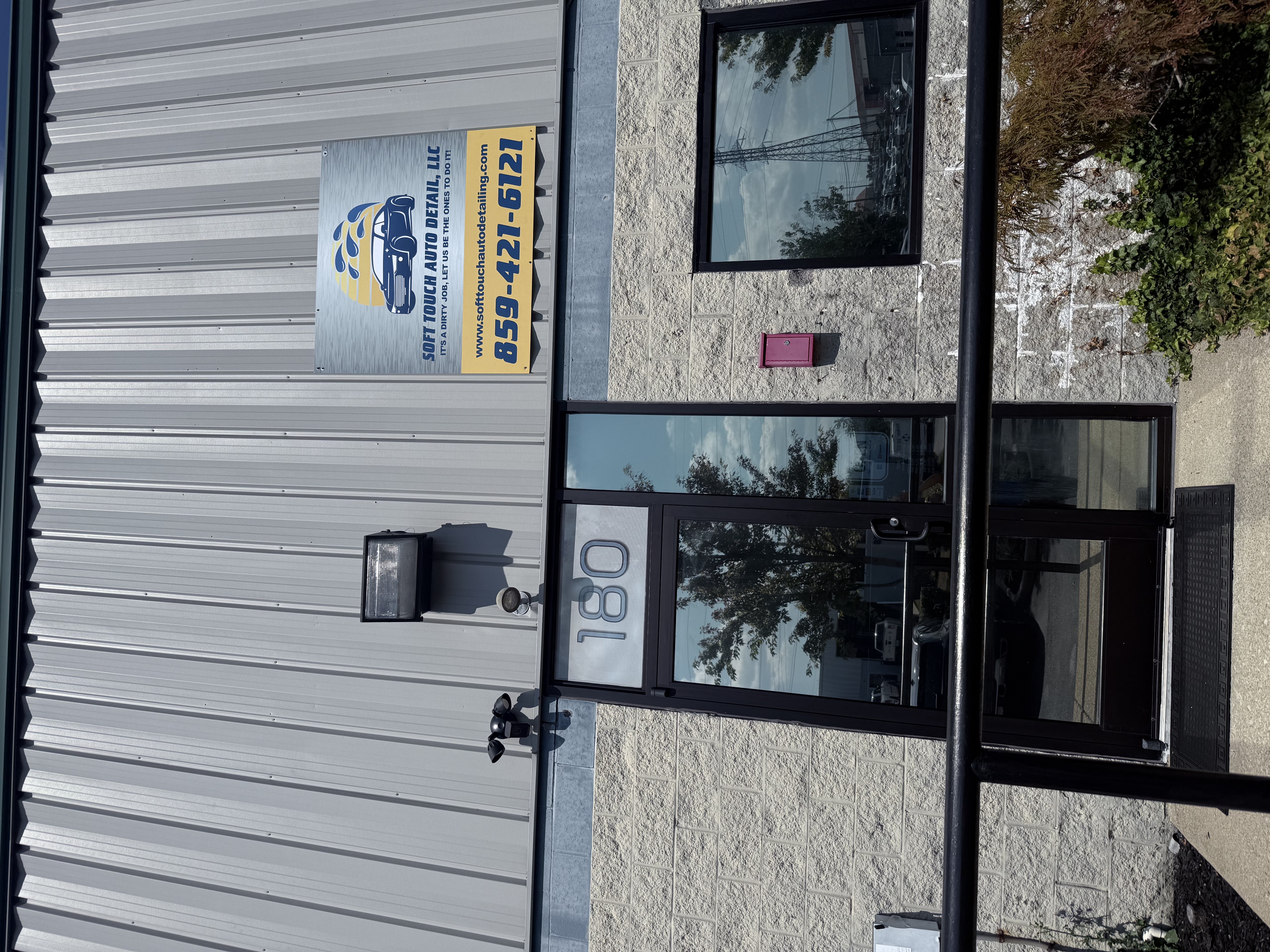 Exterior of an auto detail shop with a truck inside the open bay door, and a sign above.