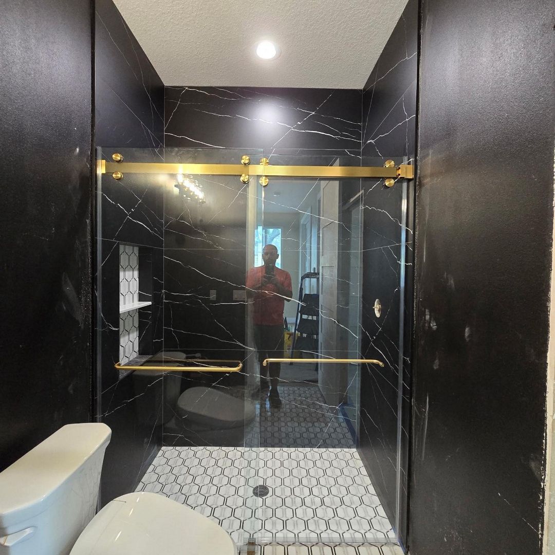 Modern bathroom with black walls, glass shower enclosure, and patterned tile floor
