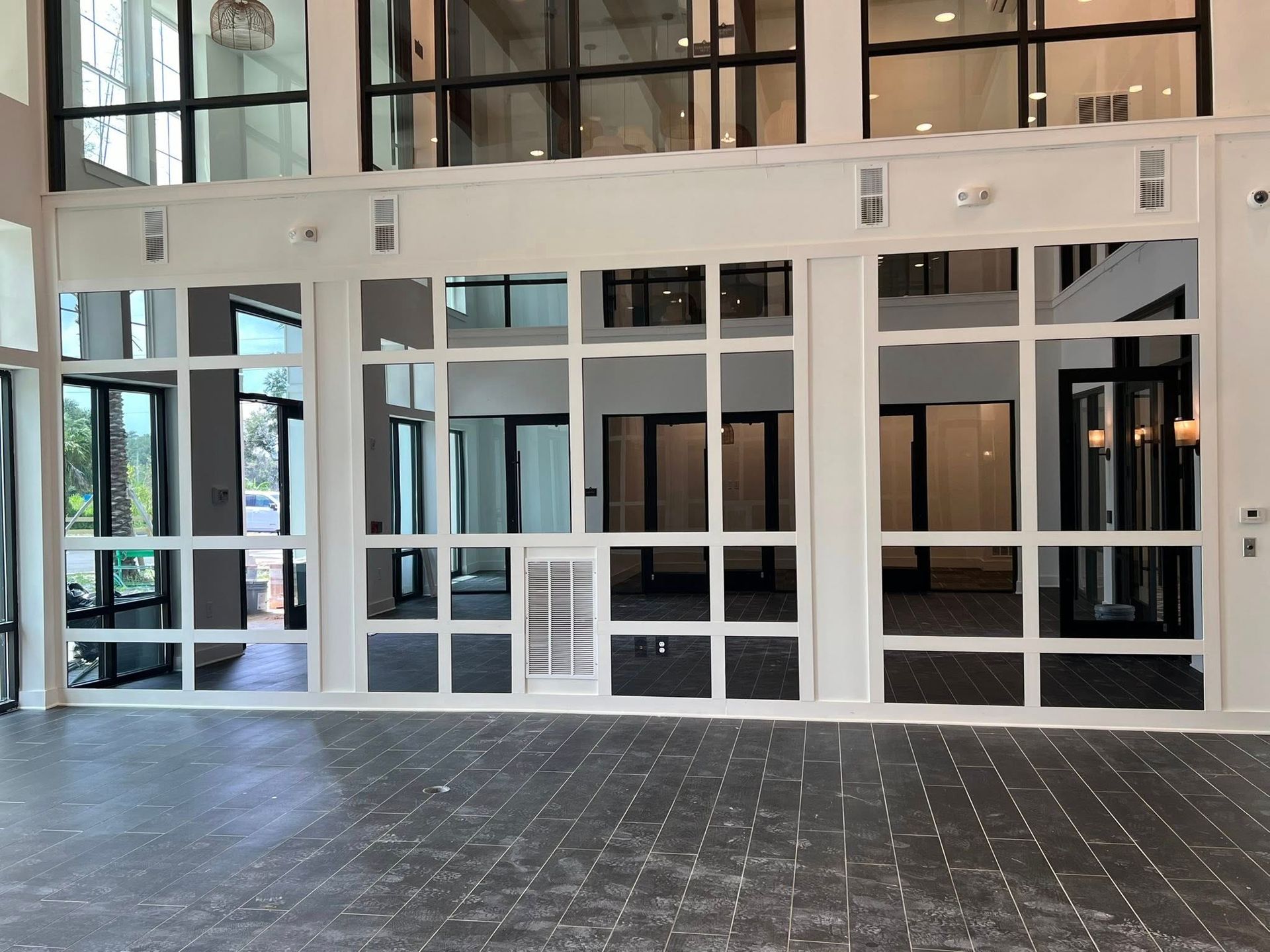 Glass-front entrance to a modern lobby with white-framed doors and large windows