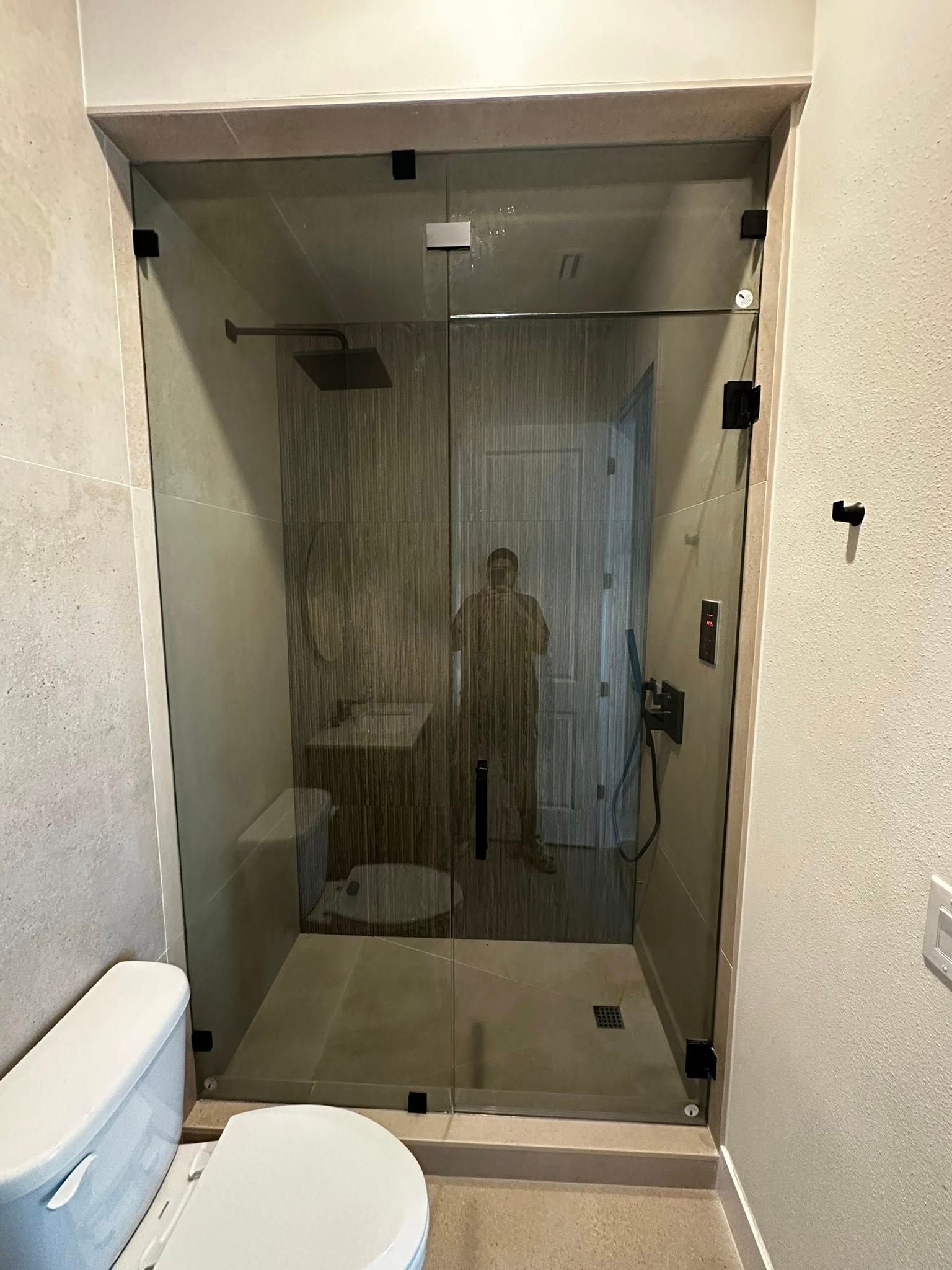 Small bathroom with toilet and sink beside a glass-enclosed shower stall.