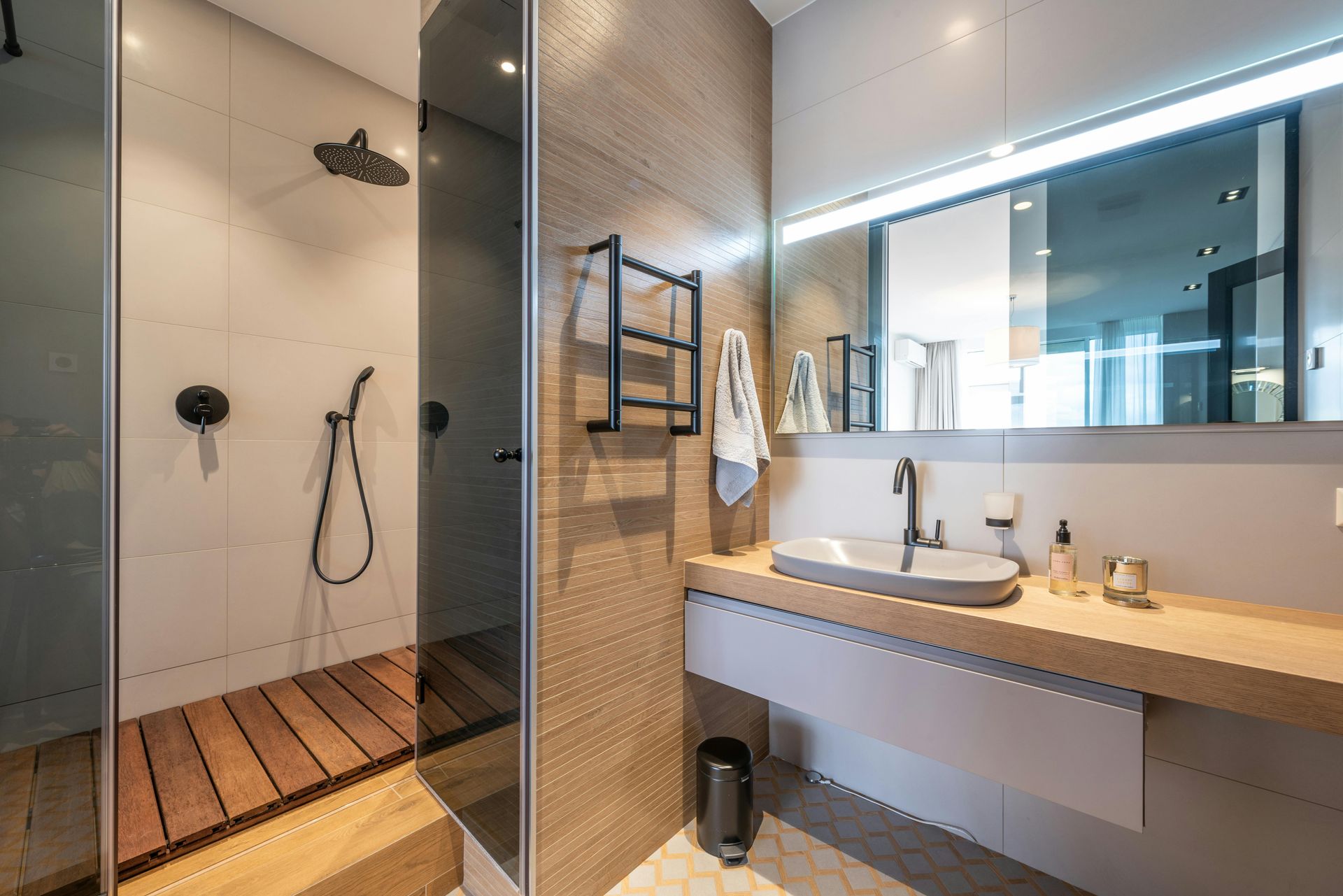 Modern bathroom featuring a wood-slatted shower floor, light-colored tiled walls, and a floating vanity with a vessel sink.