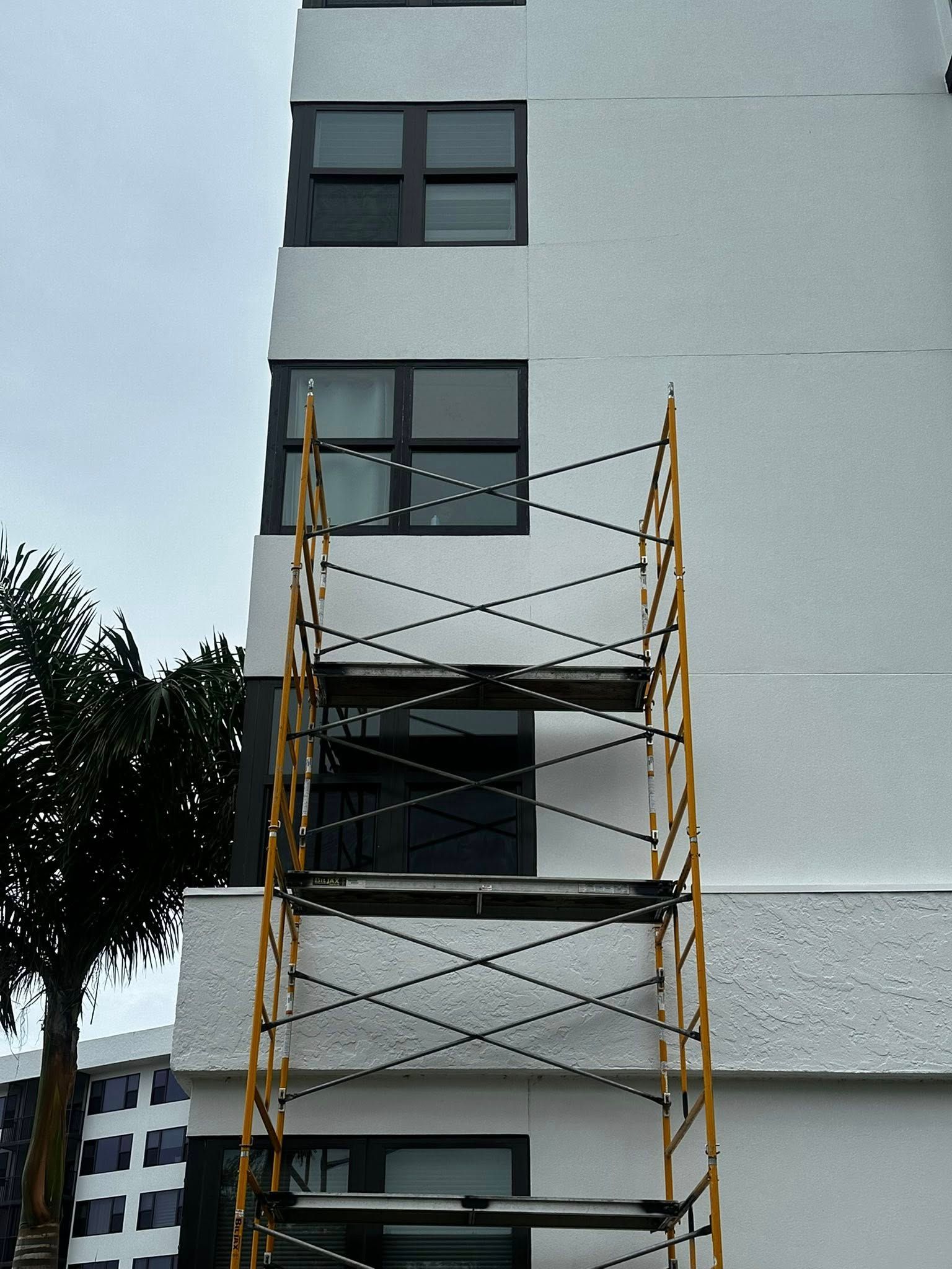 Yellow scaffolding against a gray apartment building under construction