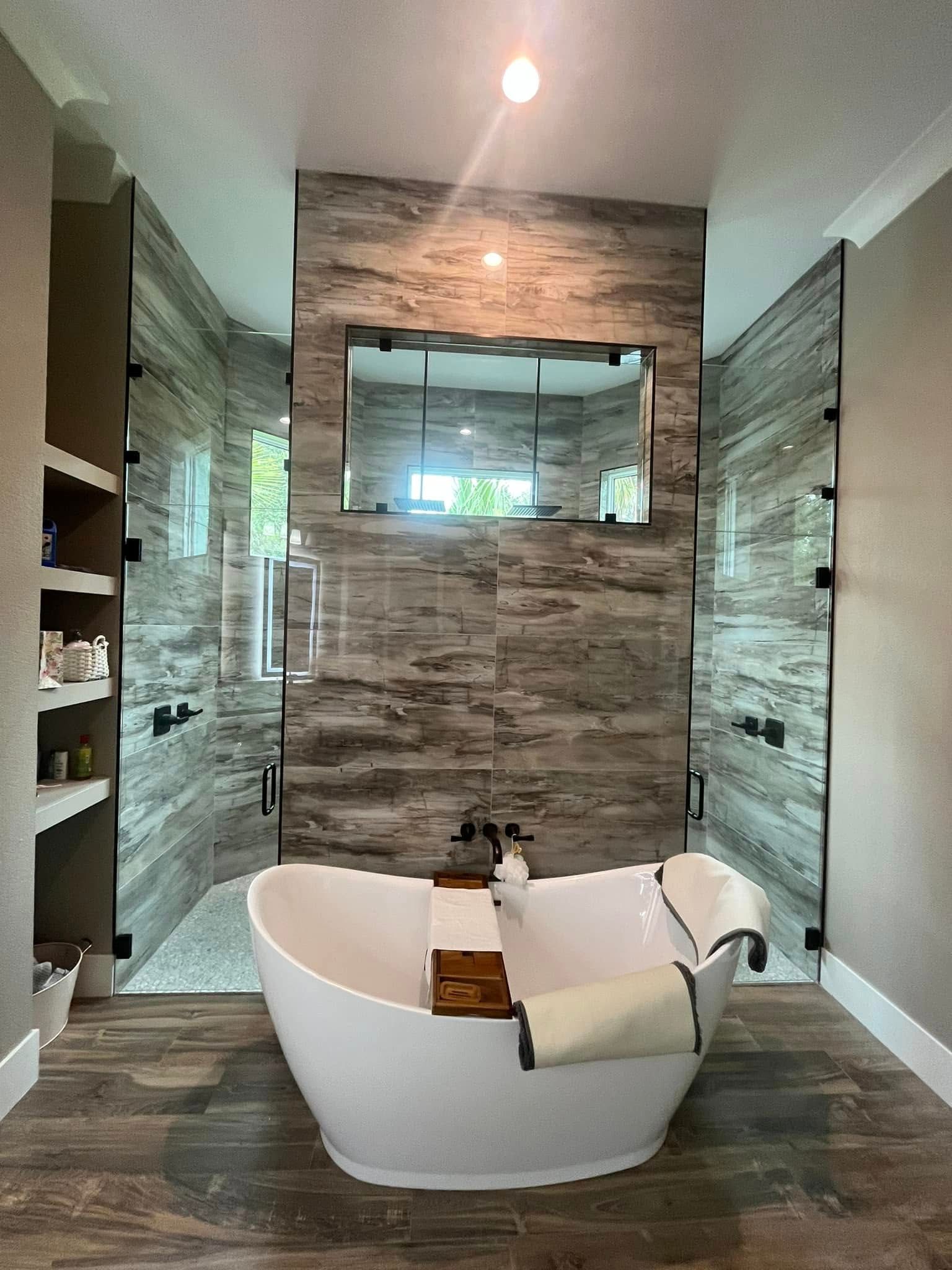 Modern bathroom with freestanding tub, walk-in shower, and gray stone tile walls.