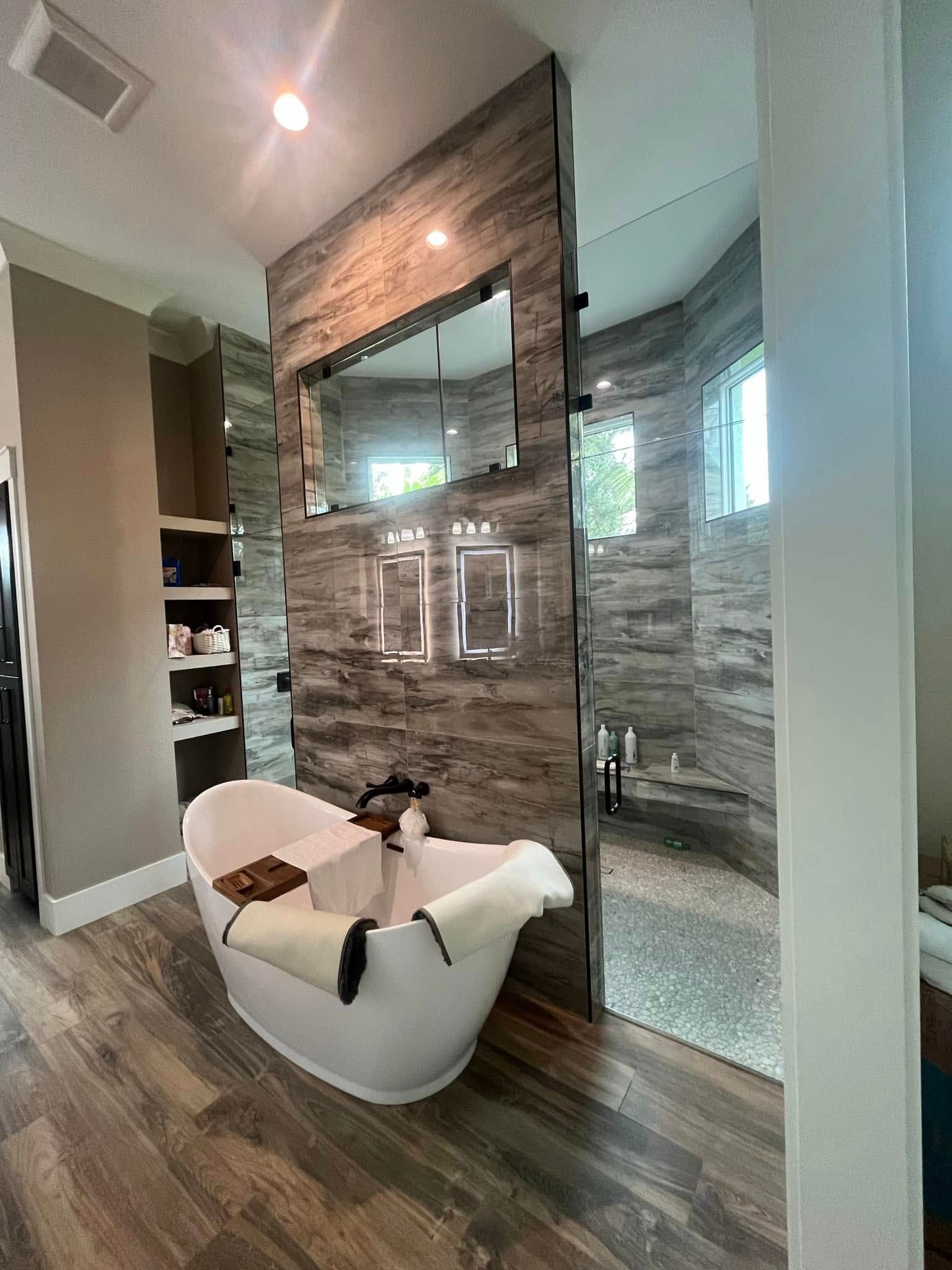 Modern bathroom with a freestanding tub, glass shower, and wood-look tile floor and walls