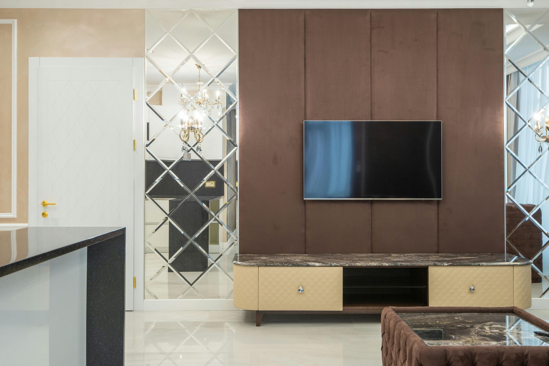 A modern living room wall features a wall-mounted TV on a brown panel above a beige, marble-topped media console.