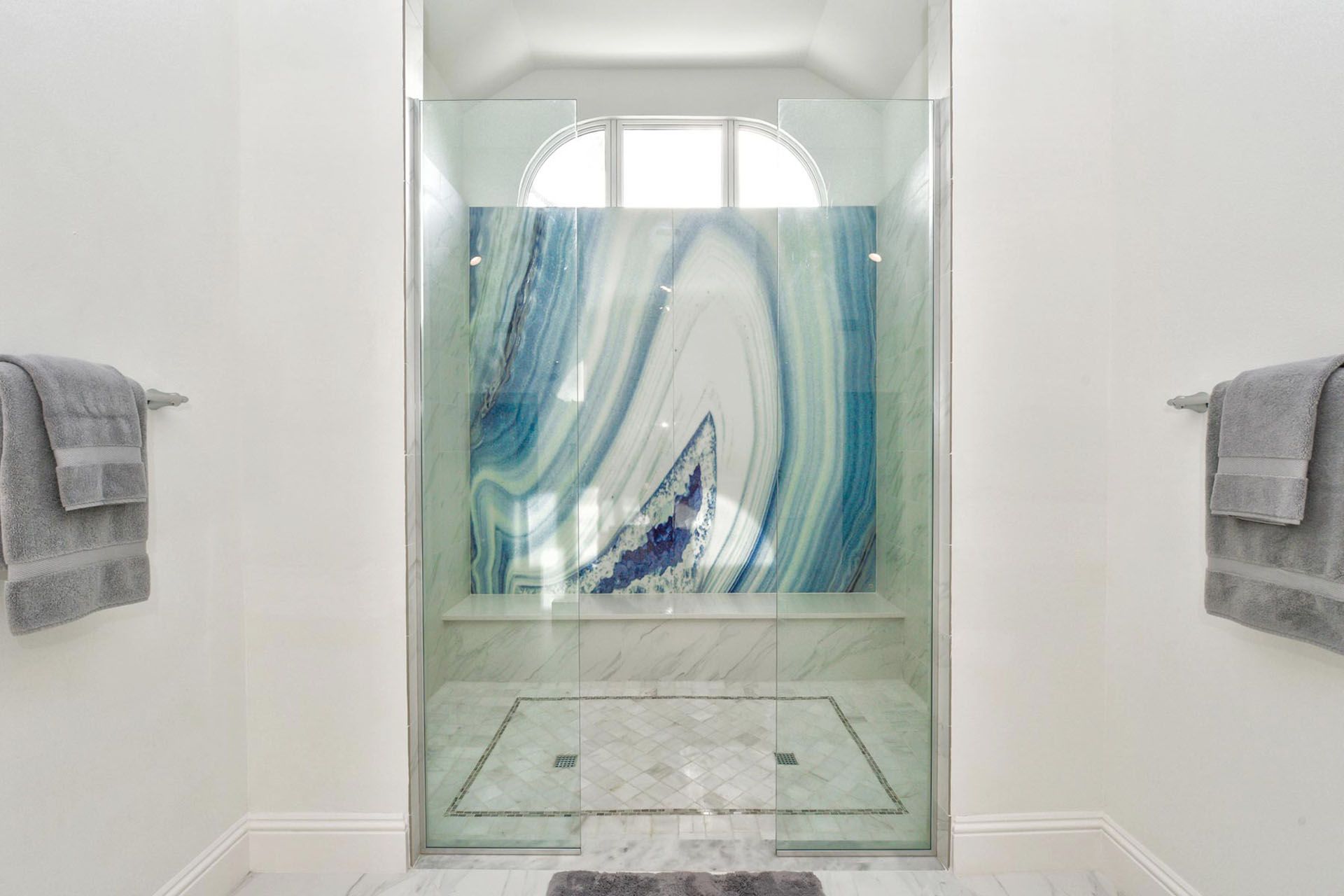 Glass shower with curtain in a bright white bathroom