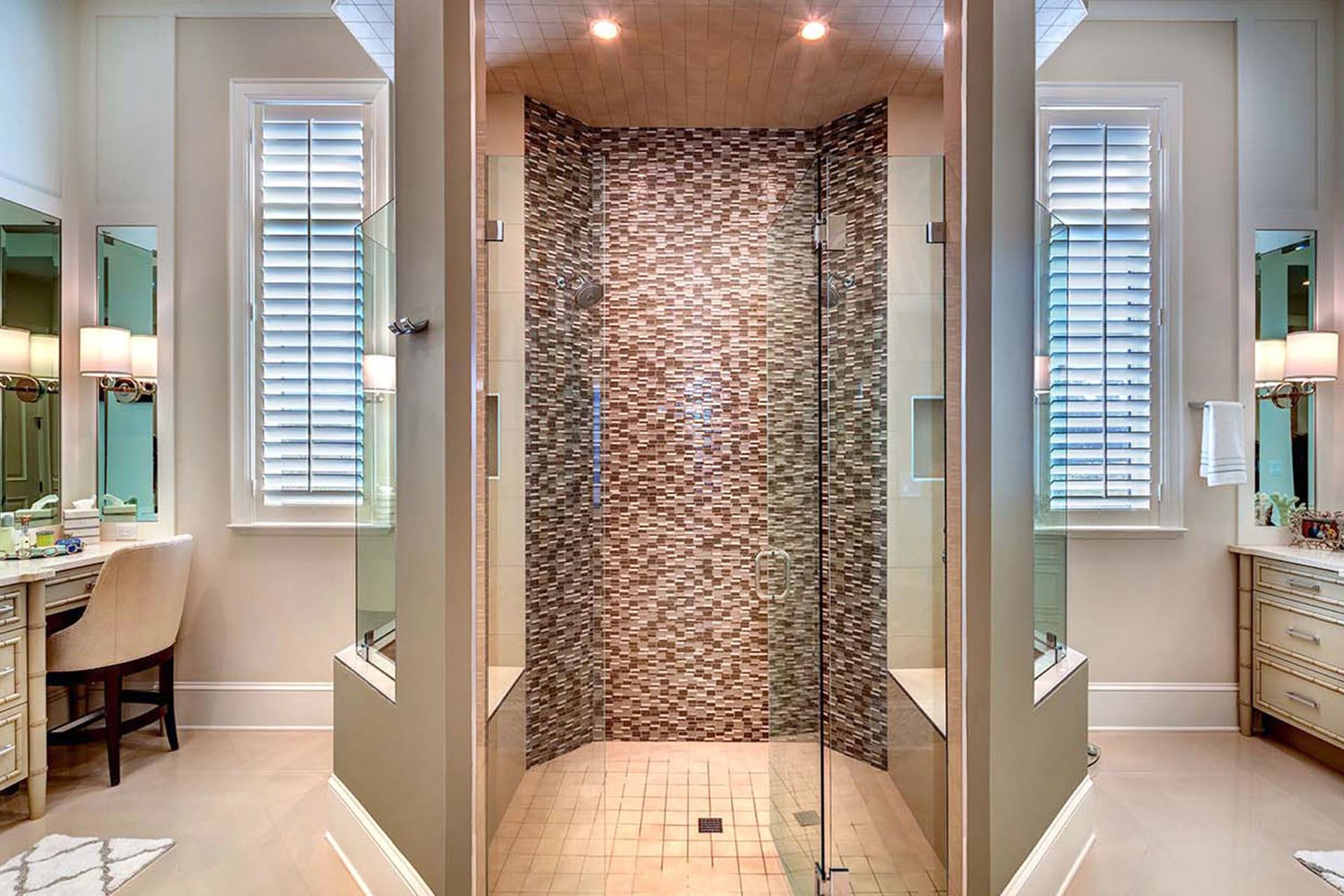 Modern bathroom with a glass shower enclosure, stone tile wall, and double vanity mirrors