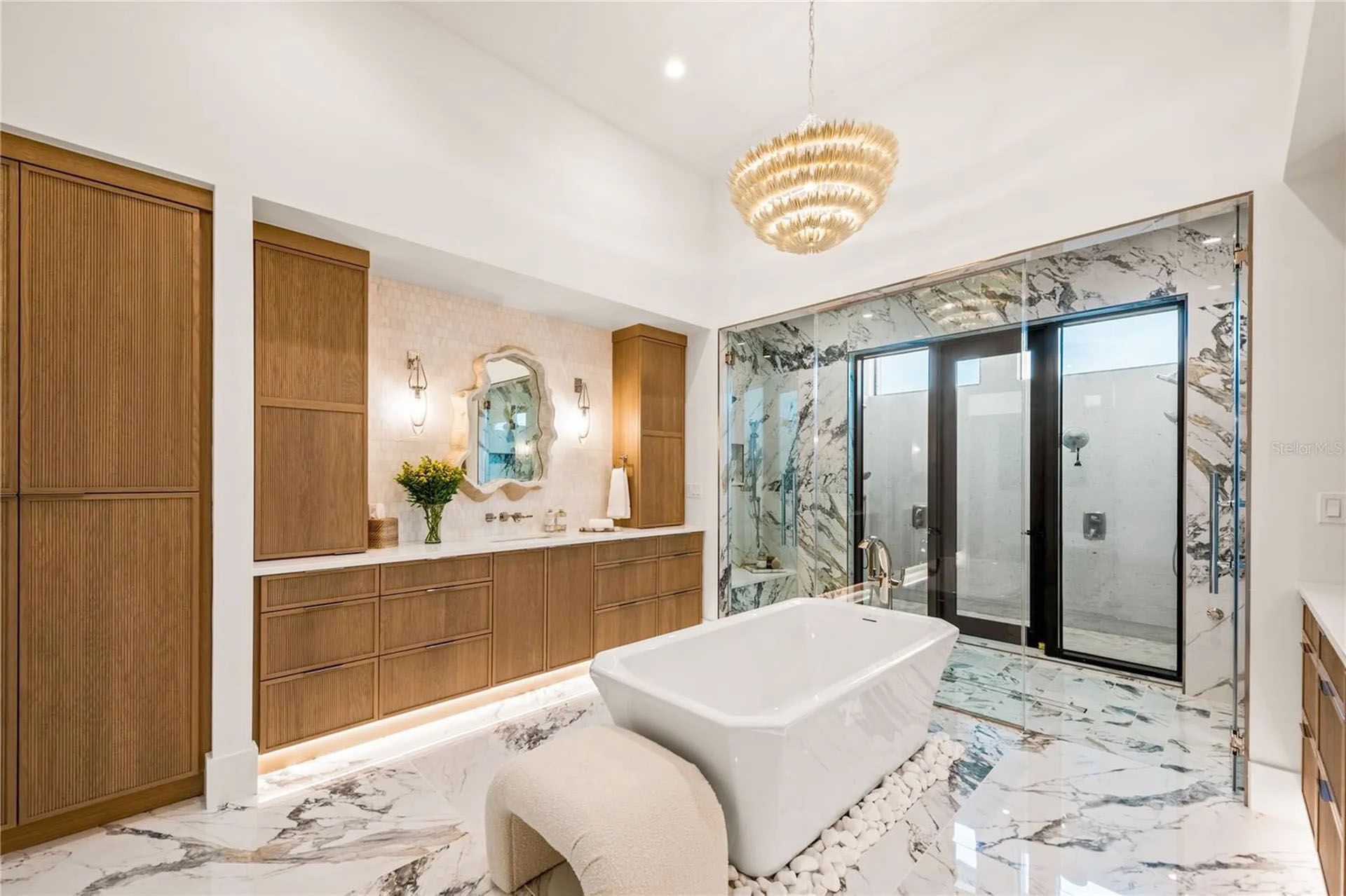 Elegant bathroom with double vanity, freestanding tub, marble floor, and glass shower enclosure