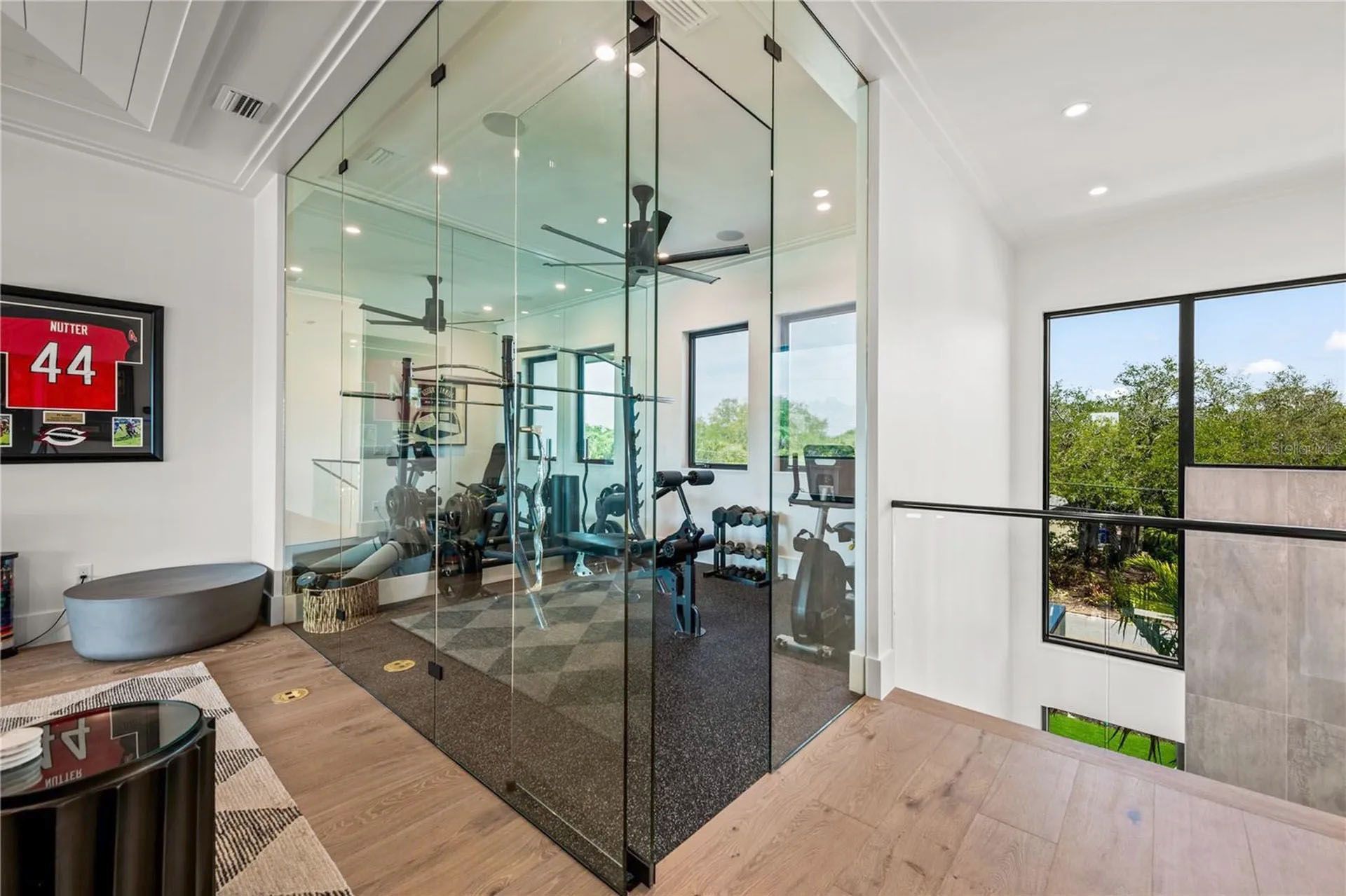 Modern home gym with glass walls, workout equipment, and large windows