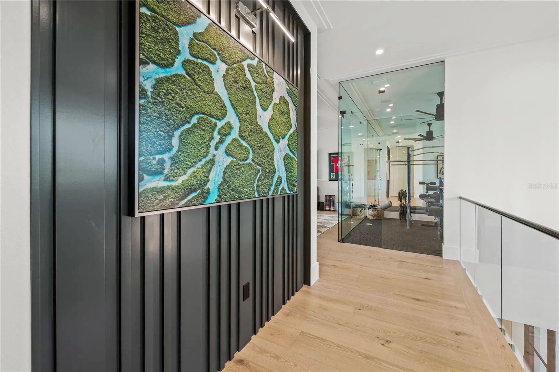 Modern hallway with wood floors, black slatted wall, and a large colorful abstract artwork