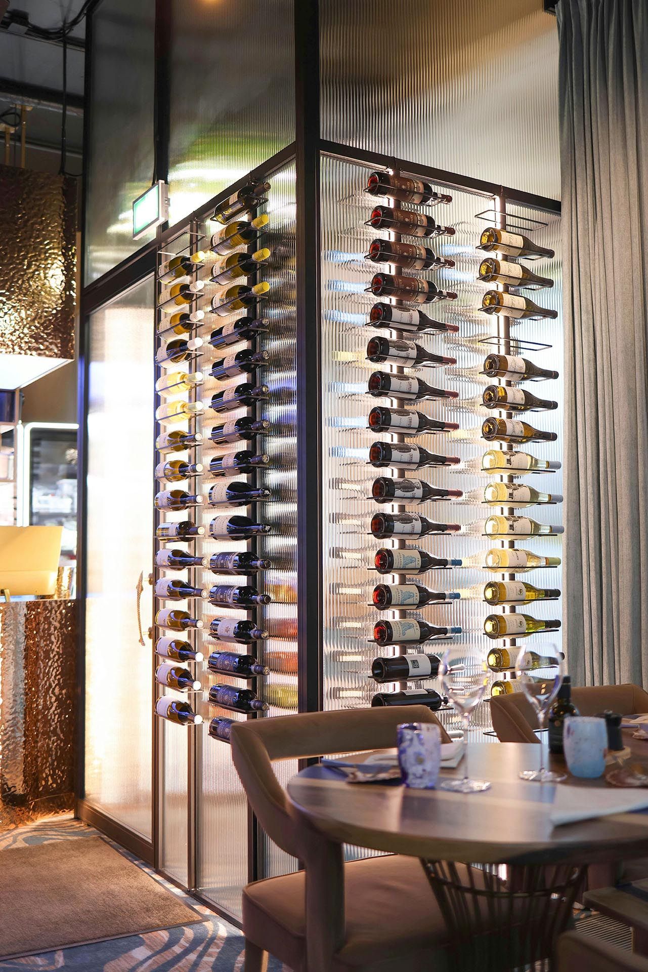 Wine display beside a table and chairs, lit with warm ambient lighting