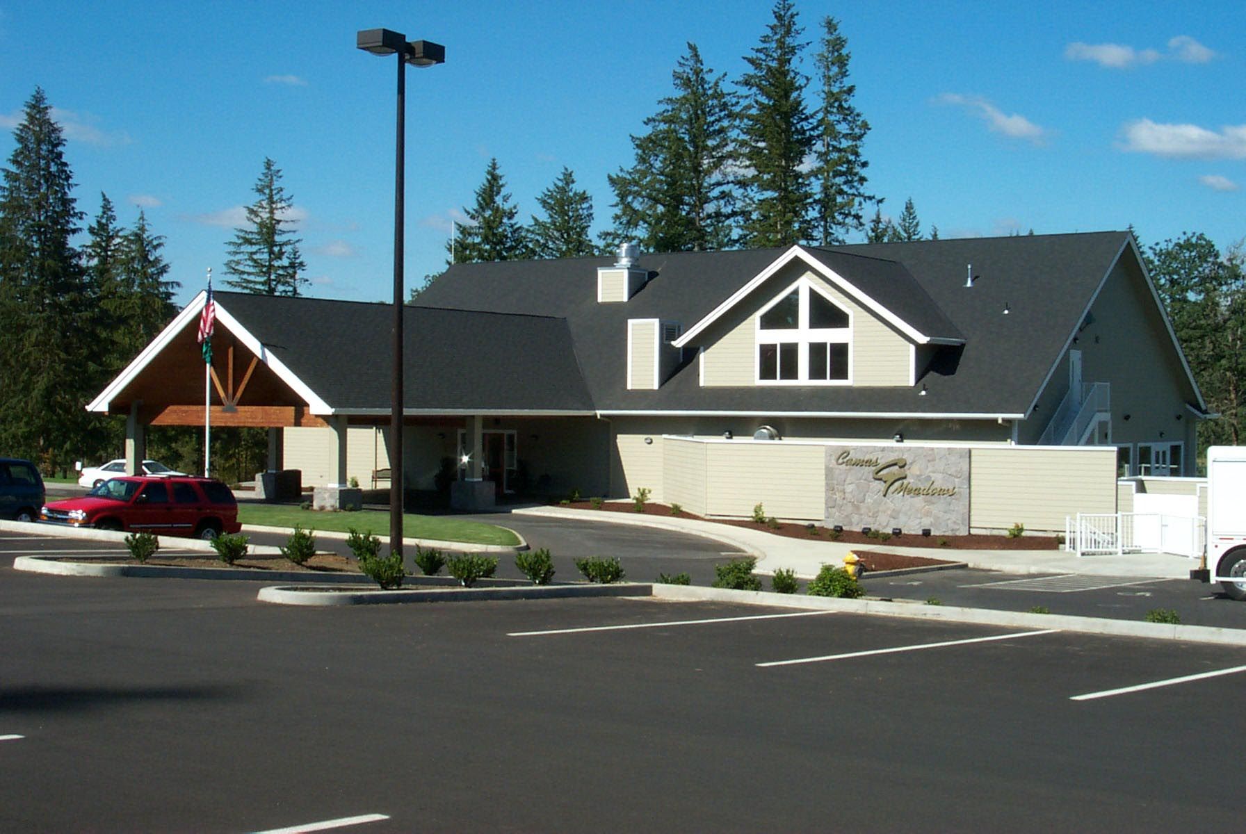 Building with angled roof and parking lot; blue sky.