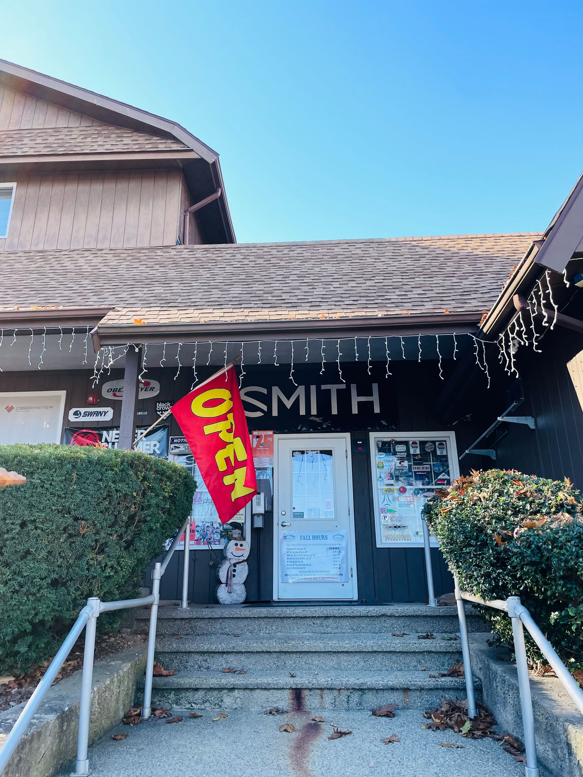 A red flag with the word open on it is hanging from the roof of a building.