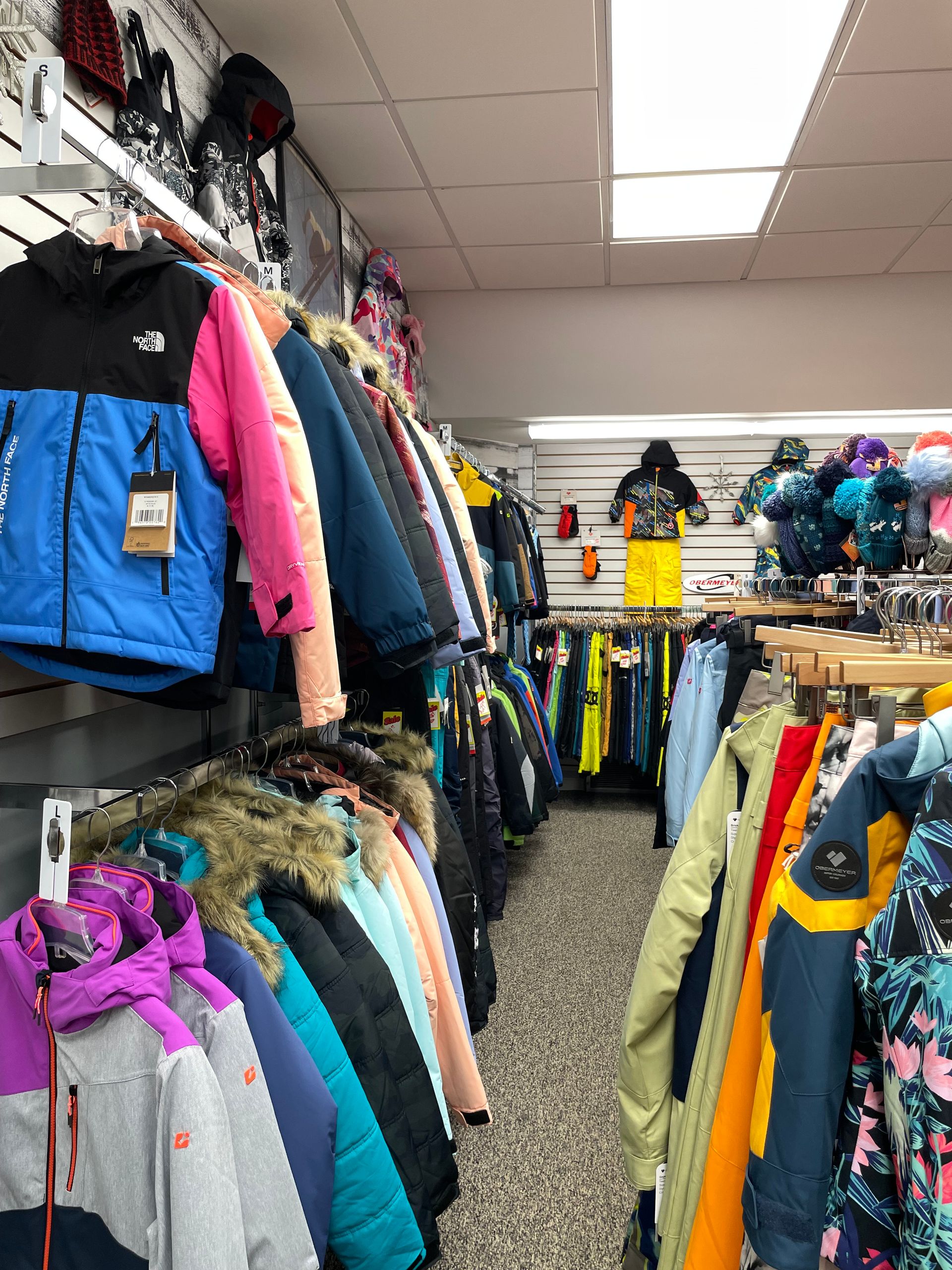 A bunch of jackets are hanging on a rack in a store.
