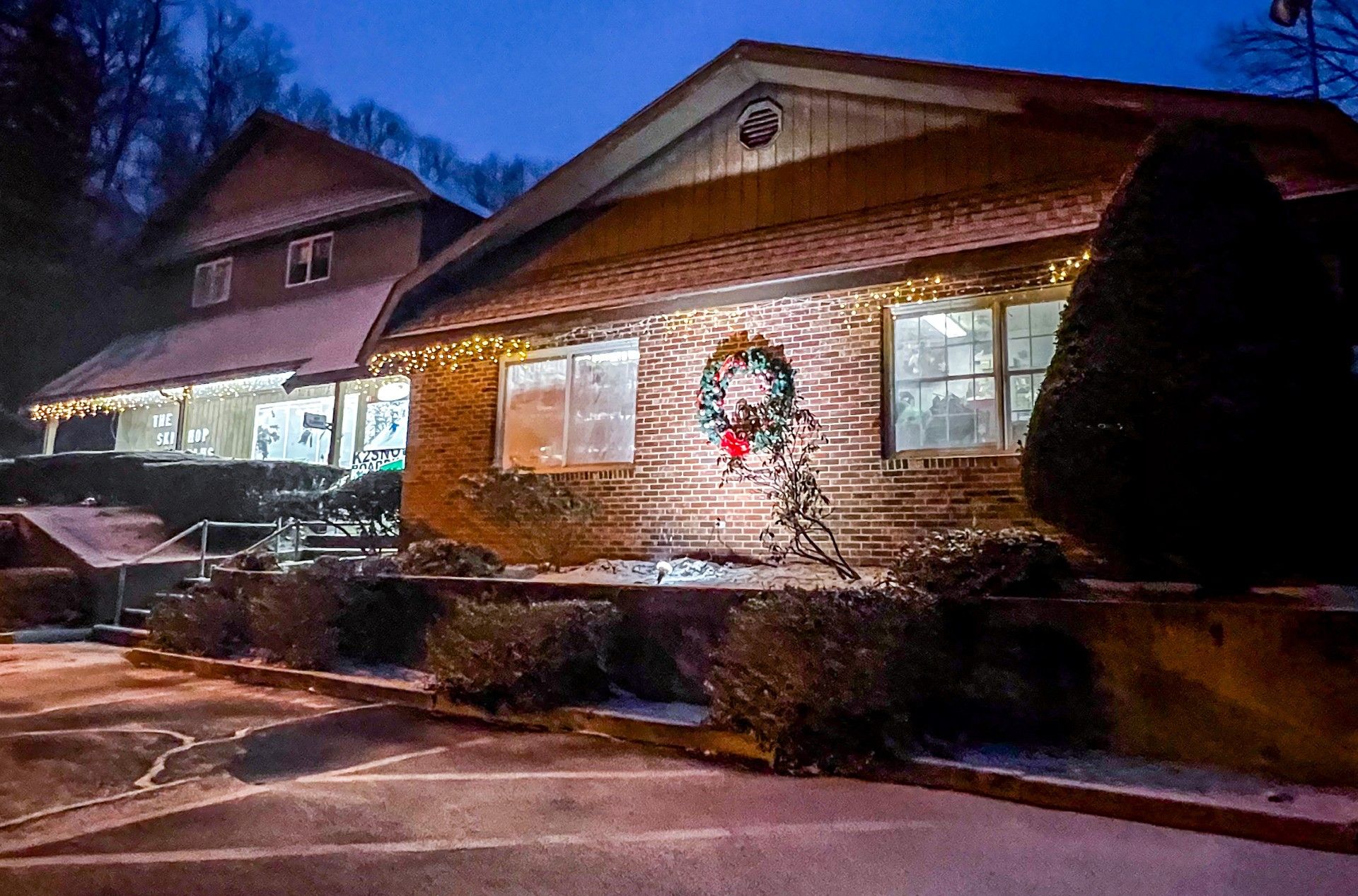 A house with a wreath on the front of it is lit up at night.