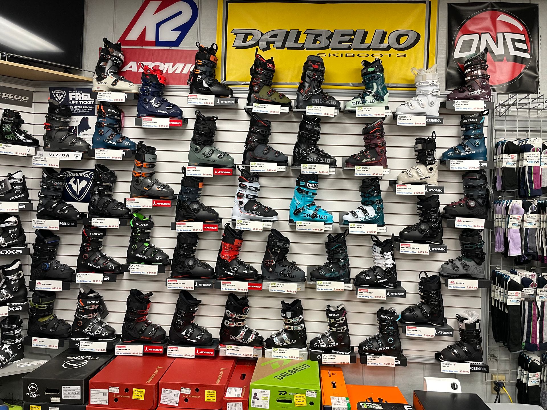 A wall filled with lots of ski boots in a store.