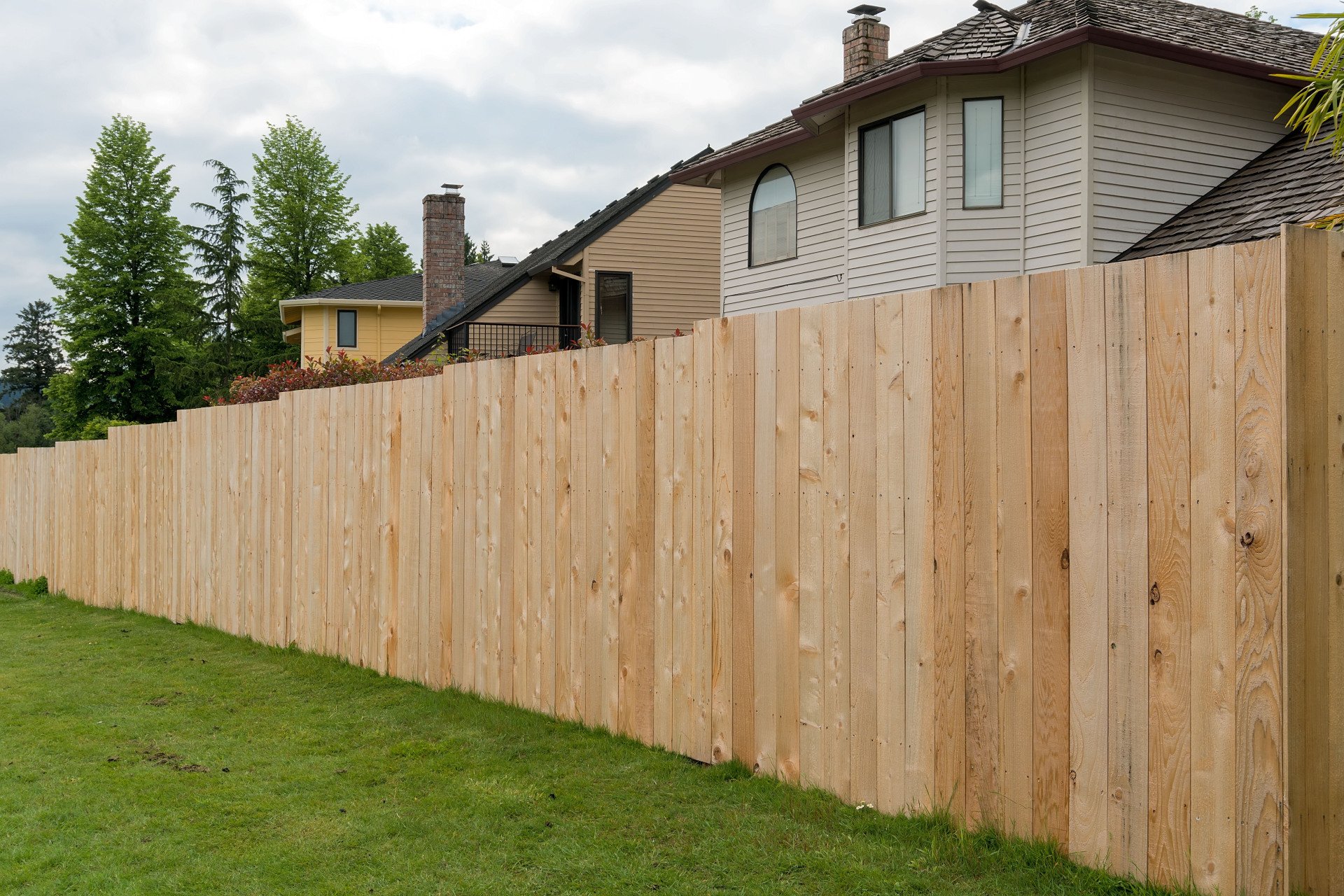 Clean wood privacy fence surrounding a lawn