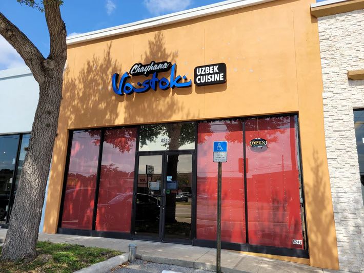 A building with a sign that says uzbek cuisine on it